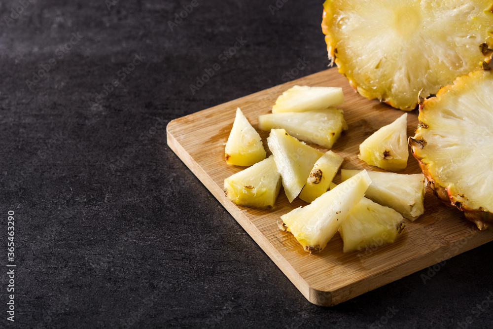 Fresh pineapple slices on cutting board and black stone background. Copy space Fresh pineapple slices on cutting board and black stone background. Copy space