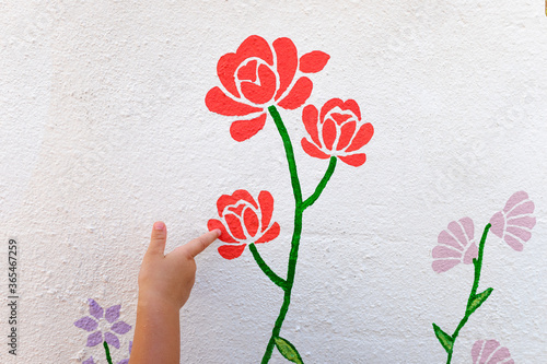 Foto Girl pointing her finger at a drawing of a painted flower on the white wall
