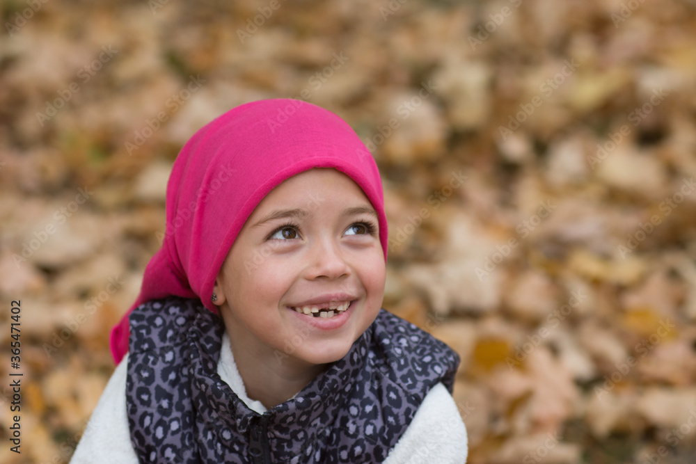 little girl in pink cap is smiling, mouth without teeth, girl portrait in autumn nature little girl in pink cap is smiling, mouth without teeth, girl portrait in autumn nature