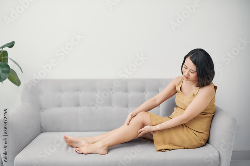 Pregnant woman massaging a swollen foot. Swelling in pregnancy. Swollen legs. Pregnant woman sitting on the sofa.