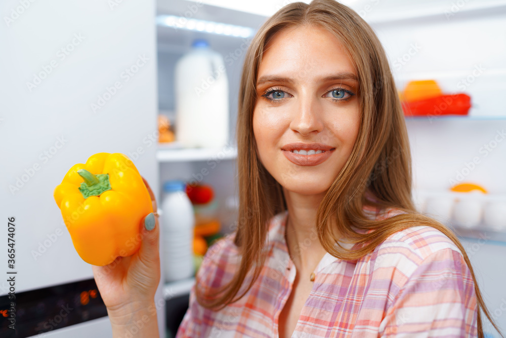 Portrait of a young blonde woman taking food from her fridge Portrait of a young blonde woman taking food from her fridge