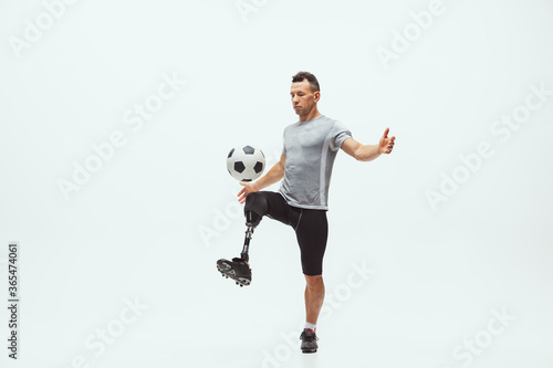 Athlete with disabilities or amputee on white studio background. Professional male football player with leg prosthesis training in studio. Disabled sport and healthy lifestyle concept. Achievements. © master1305