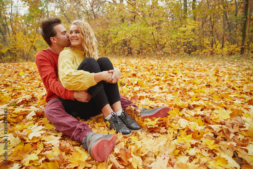 Young happy couple relaxing and loving in the autumn forest at sunset. Young happy couple relaxing and loving in the autumn forest at sunset.
