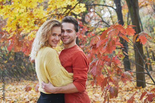Young happy couple relaxing and loving in the autumn forest at sunset.