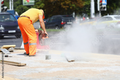 Male worker holds gas cutter in his hands and cuts concrete. Construction road work concept