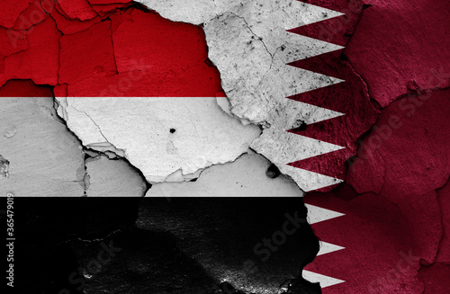 flags of Yemen and Qatar painted on cracked wall