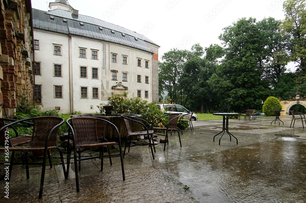 Naklejka premium Empty tables in the castle courtyard during the rain