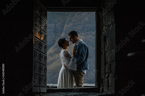 Young Georgian couple posing in the mountains. Boho wedding in Georgia. Evening setting sun. Blue jeans jacket
