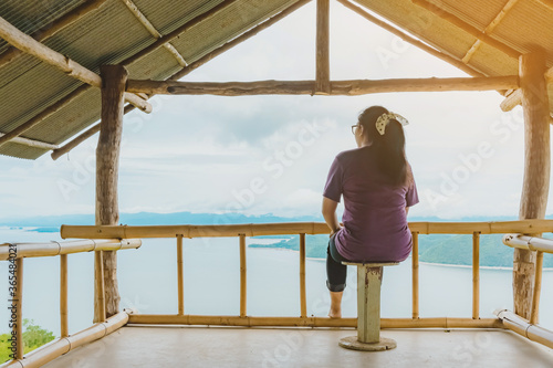 Back view of woman enjoy with beautiful scenery view of nature with a large reservoir above the Srinagarind Dam at Rai Ya Yam view point in Si Sawat District, Kanchanaburi Thailand.