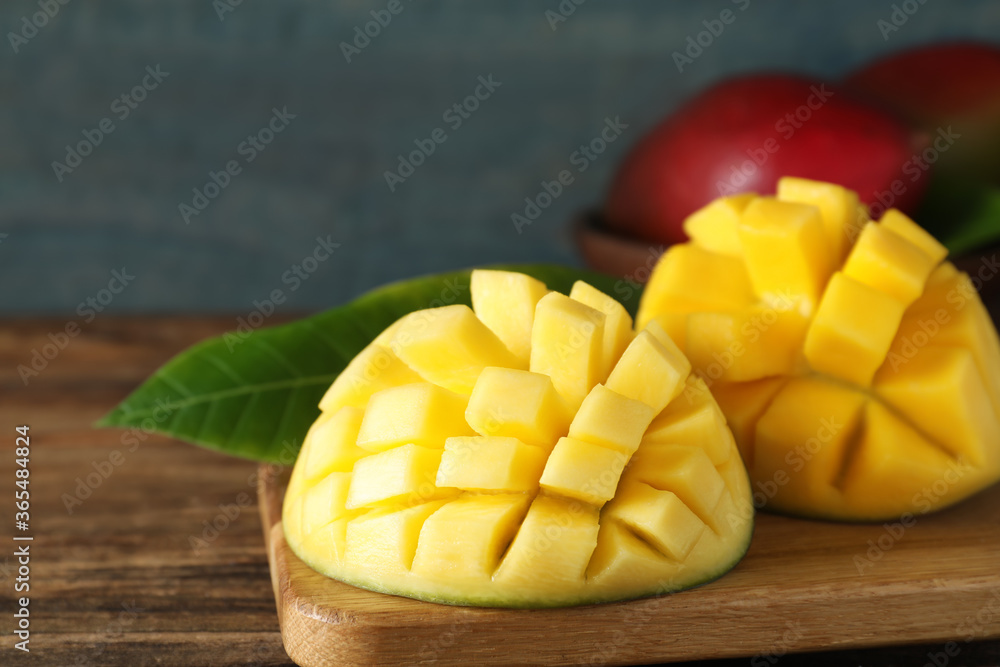 Halves of ripe mango cut into cubes on wooden table