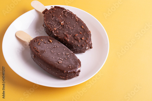 tasty cold chocolate ice cream with nuts pieces on wooden stick
