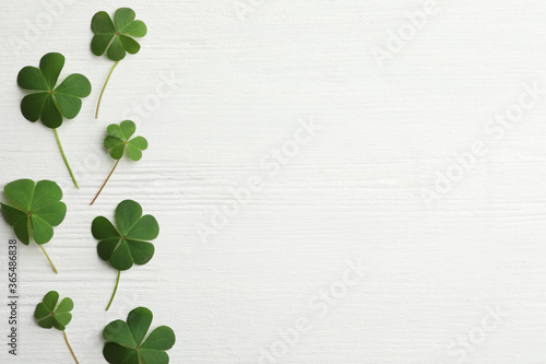 Clover leaves on white wooden table, flat lay with space for text. St. Patrick's Day symbol