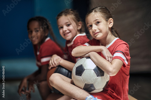 Girl with soccer ball in good mood before training in changing room.