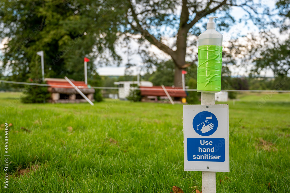 Hand sanitiser and Covid-19 reminder sign at an outdoor horse trials event Hand sanitiser and Covid-19 reminder sign at an outdoor horse trials event