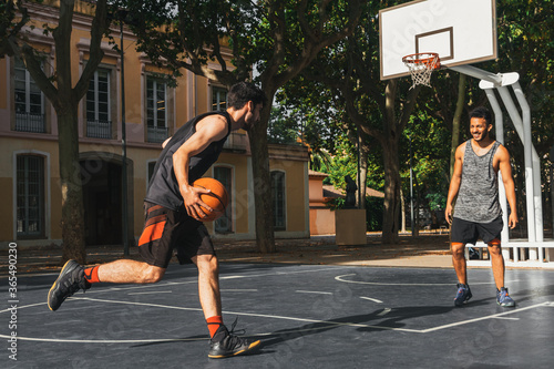 two young men play basketball outdoors