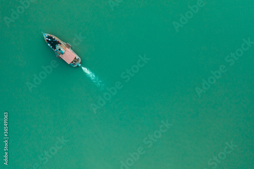 The boat is sailing on a mountain lake. Rich emerald color of water. Free space for your text
