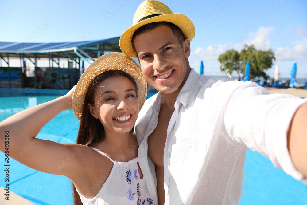 Happy couple taking selfie near swimming pool. Summer vacation
