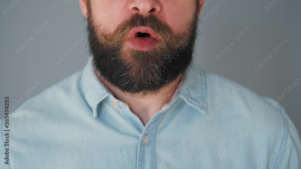Bearded man with curled up mustache eating chocolate chip cookies on a gray wall background Bearded man with curled up mustache eating chocolate chip cookies on a gray wall background