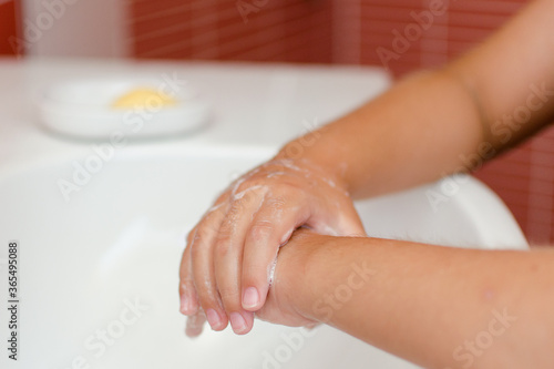 Detalle de las manos de un niño que se está lavando con jabón