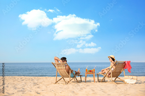 Couple resting on sunny beach at resort. Space for text