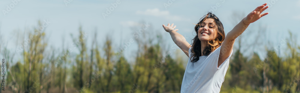 horizontal crop of cheerful woman with outstretched hands smiling outside