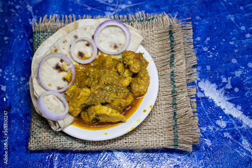 Mangsho Kosha or Bengali Style Chicken Curry with Roti  or Chapati in a Plate Isolated Bluish Background photo