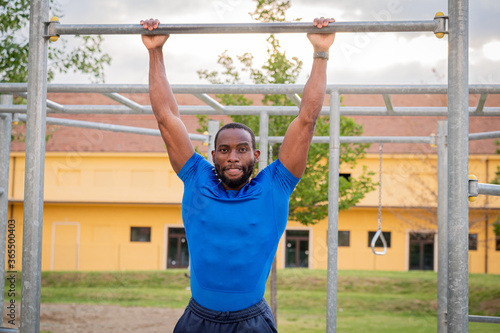 Athlete doing pull-up on horizontal bar - Fitness outdoor in the park - Afro or african american man outdoor at city. Pull up sport exercises. fitness, health, lifestyle concept