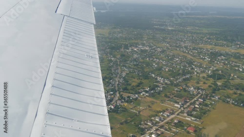 The white wing of a passenger plane against the top view of nature backdrop of a beautiful blue lake, flies over a pond, green forests and small houses and towns. Travel concept. photo