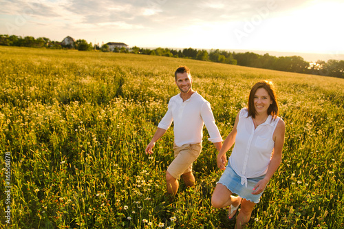 young couple kissing on the background of a sunset in the field