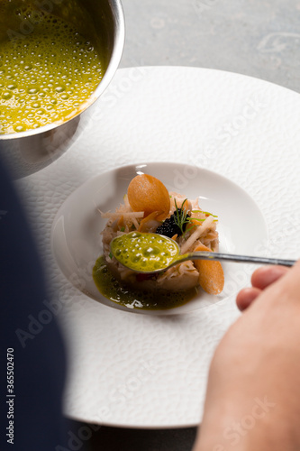 Fototapeta Naklejka Na Ścianę i Meble -  Chef cuisinier verse sauce sur plat gastronomique à base de fruits de mer