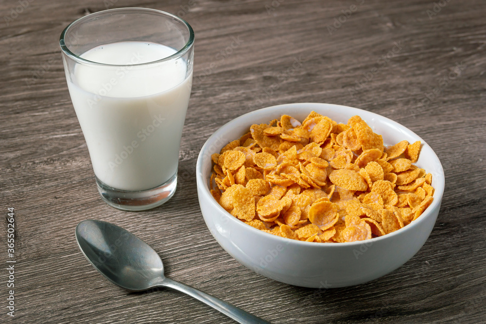 Bowl with healthy cornflakes and milk on light table Bowl with healthy cornflakes and milk on light table