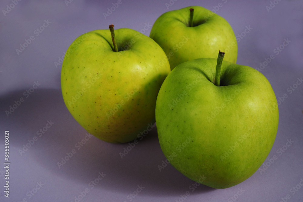 three large green Golden apples on a lilac background . organic fruits rich in iron three large green Golden apples on a lilac background . organic fruits rich in iron