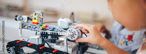 Two schoolgirls study in a robotics class, assemble a robot constructor