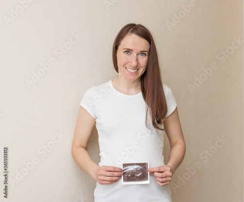 A happy pregnant woman shows her ultrasound picture. The concept of motherhood