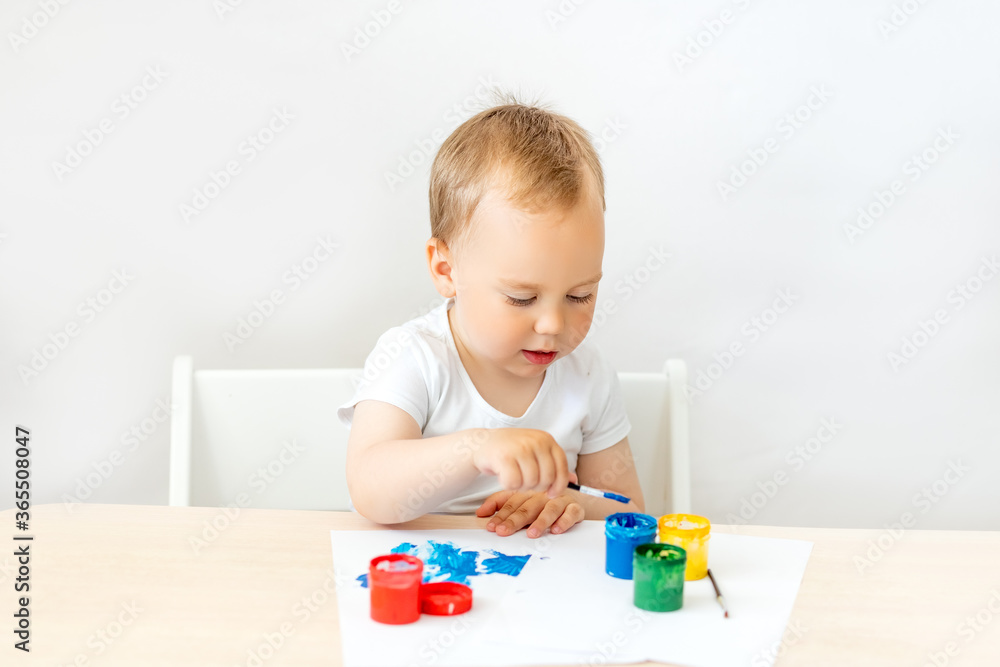 child boy 2 years old sitting at a table on a white isolated background and paints, early development, place for text child boy 2 years old sitting at a table on a white isolated background and paints, early development, place for text
