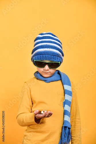 A boy with glasses in a hat and scarf looks at the compass so as not to get lost.