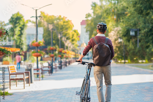 Male commuter wearing bike helmet walking away. Safe cycling in city, bicycle commuting, active urban lifestyle image photo