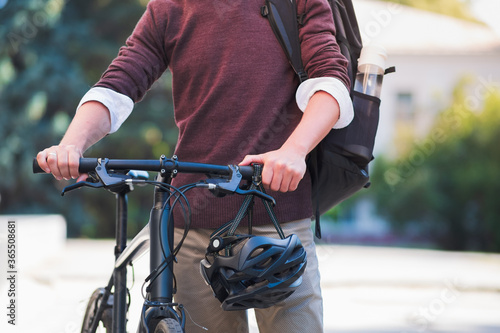 Commuter bike in hands of a male millennial, urban background. Safe cycling in the city, active urban lifestyle concept