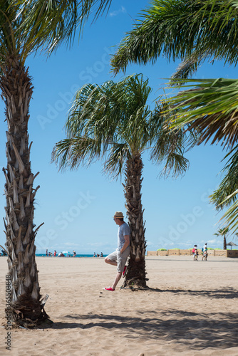 Portrait of man standing near a palm tree on the beach in Valras in south of France photo