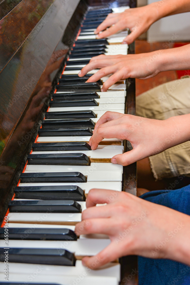 Fototapeta premium Brother and sister play the piano with four hands. Children learn the art of music.