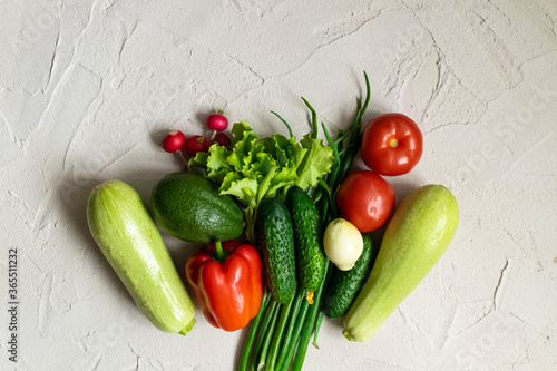 Assortment of fresh green red organic vegetables on a concrete background.