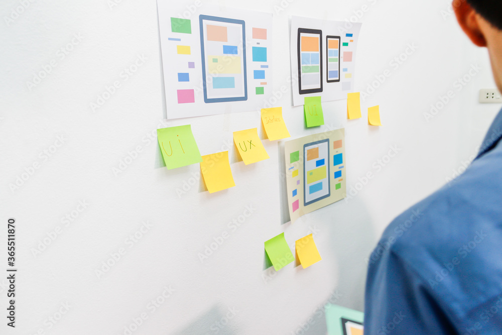 The team of website designers with the ux ui system are writing programs and laying the layer to determine the display style with the ux ui system within the front of the smartphone. The team of website designers with the ux ui system are writing programs and laying the layer to determine the display style with the ux ui system within the front of the smartphone.