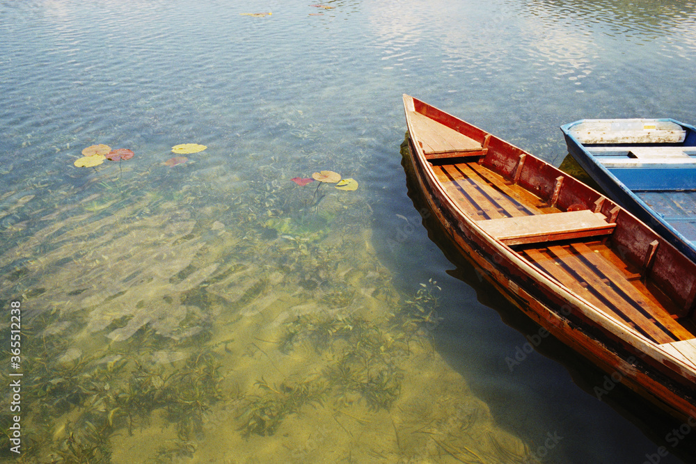 Obraz premium Panoramic view of old flooded fishing boats on a mountain lake in the town of Plav in Montenegro. Real grain scanned film.