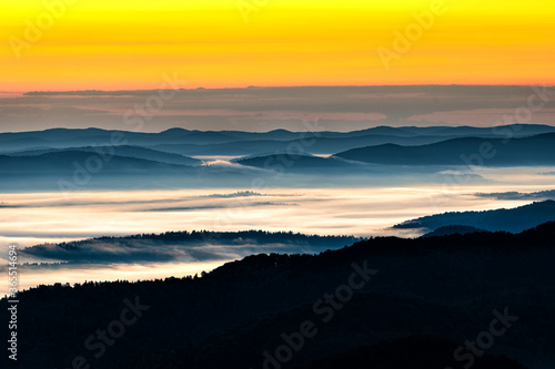 Fototapeta Naklejka Na Ścianę i Meble -  A hazy sunrise in the mountains. Mountains silhouettes and fog in the valleys. Photo from Polonina Wetlinska. Bieszczady National Park. Carpathians. Poland.