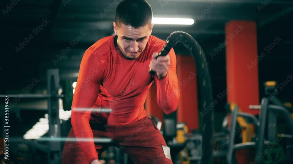 A man trains with ropes, lifting them. A man trains with ropes, lifting them.