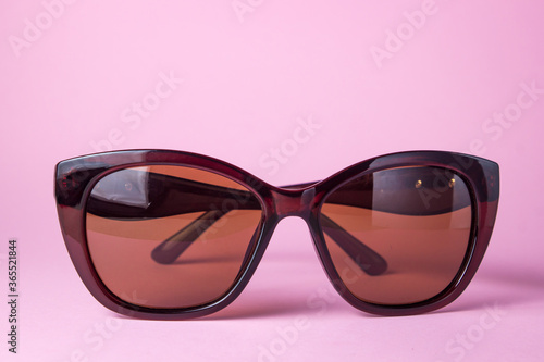 Female glasses on a pink background. Brown sunglasses for women lie on a pink surface. Female glamor