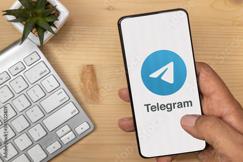 Lutsk, Ukraine - July 17, 2020: Hand Holding and tapping smartphone with Telegram Logo on it with according text. photo