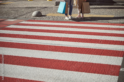 Two ladies with shopping bags in hands waiting near the road