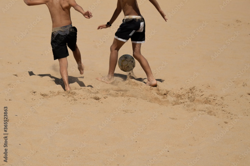 children playing in the sand with the ball