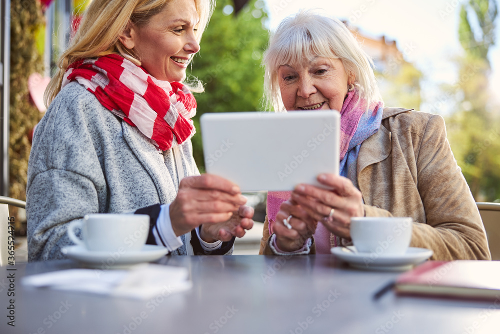 Happy two ladies spending time with modern tablet Happy two ladies spending time with modern tablet